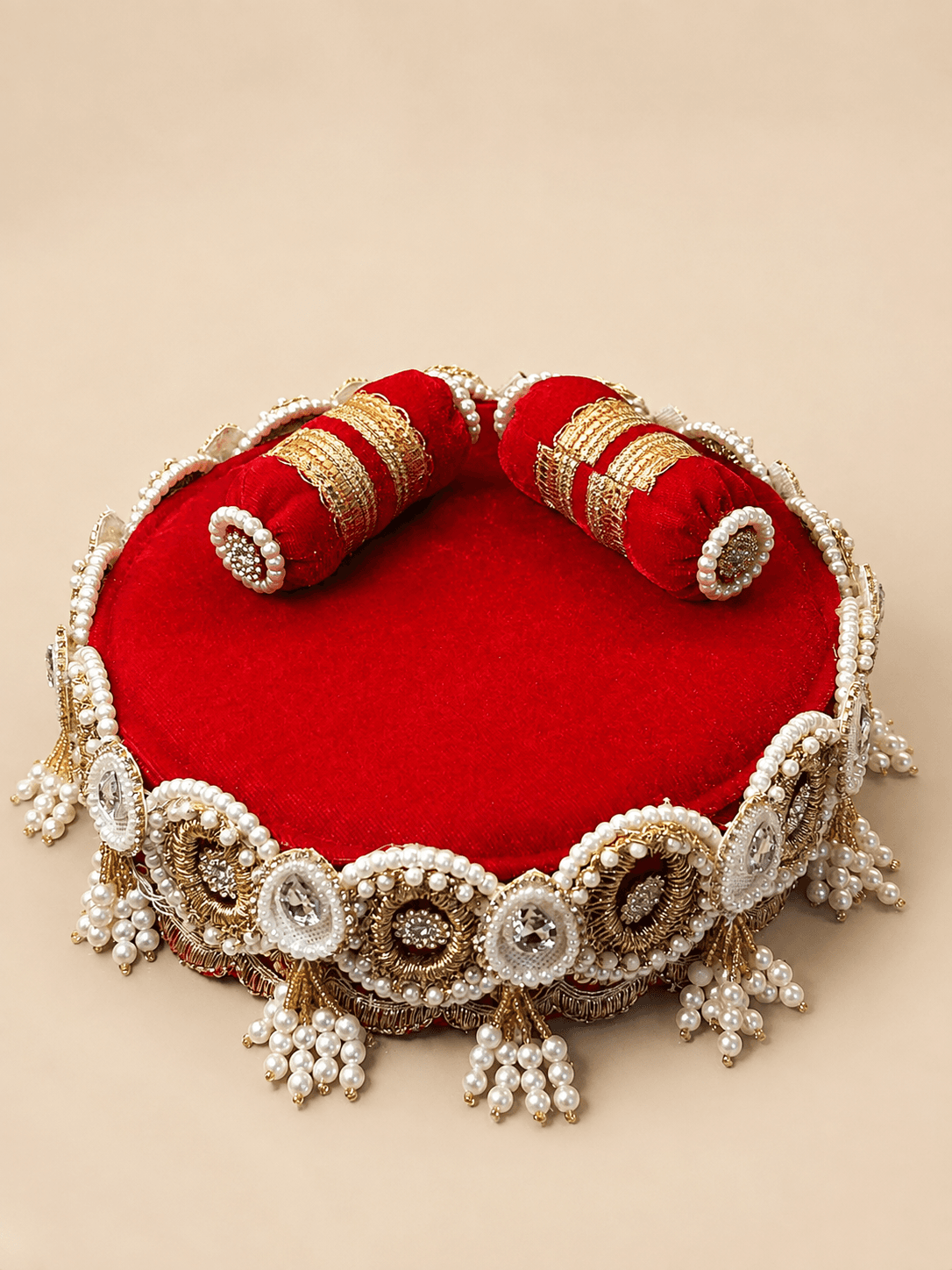 Crimson velvet gadi with zari-banded bolsters and a heavy zardosi and pearl border