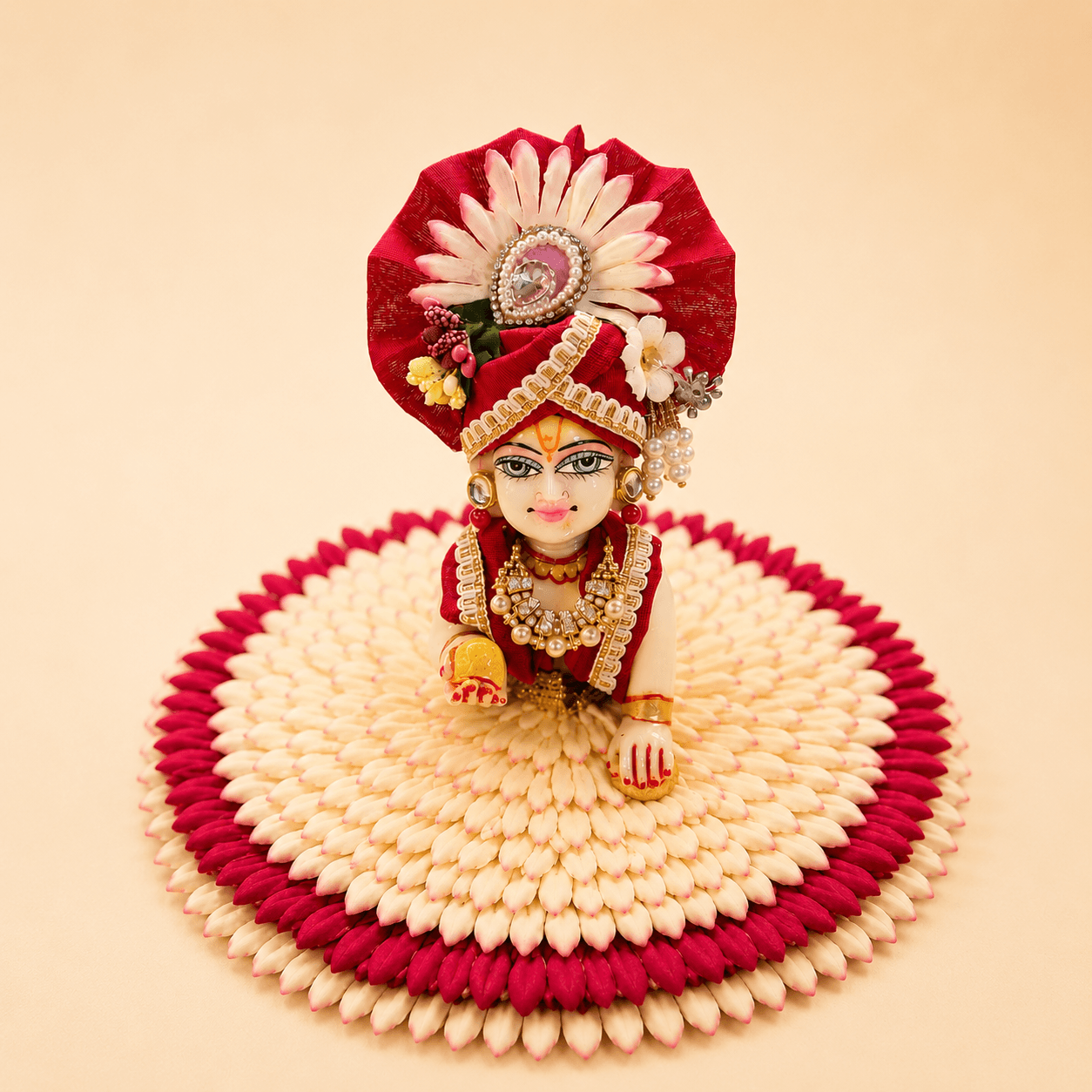 Laddu Gopal dressed in a crimson silk wagha with a pearl-set pagh, seated on a flower asan